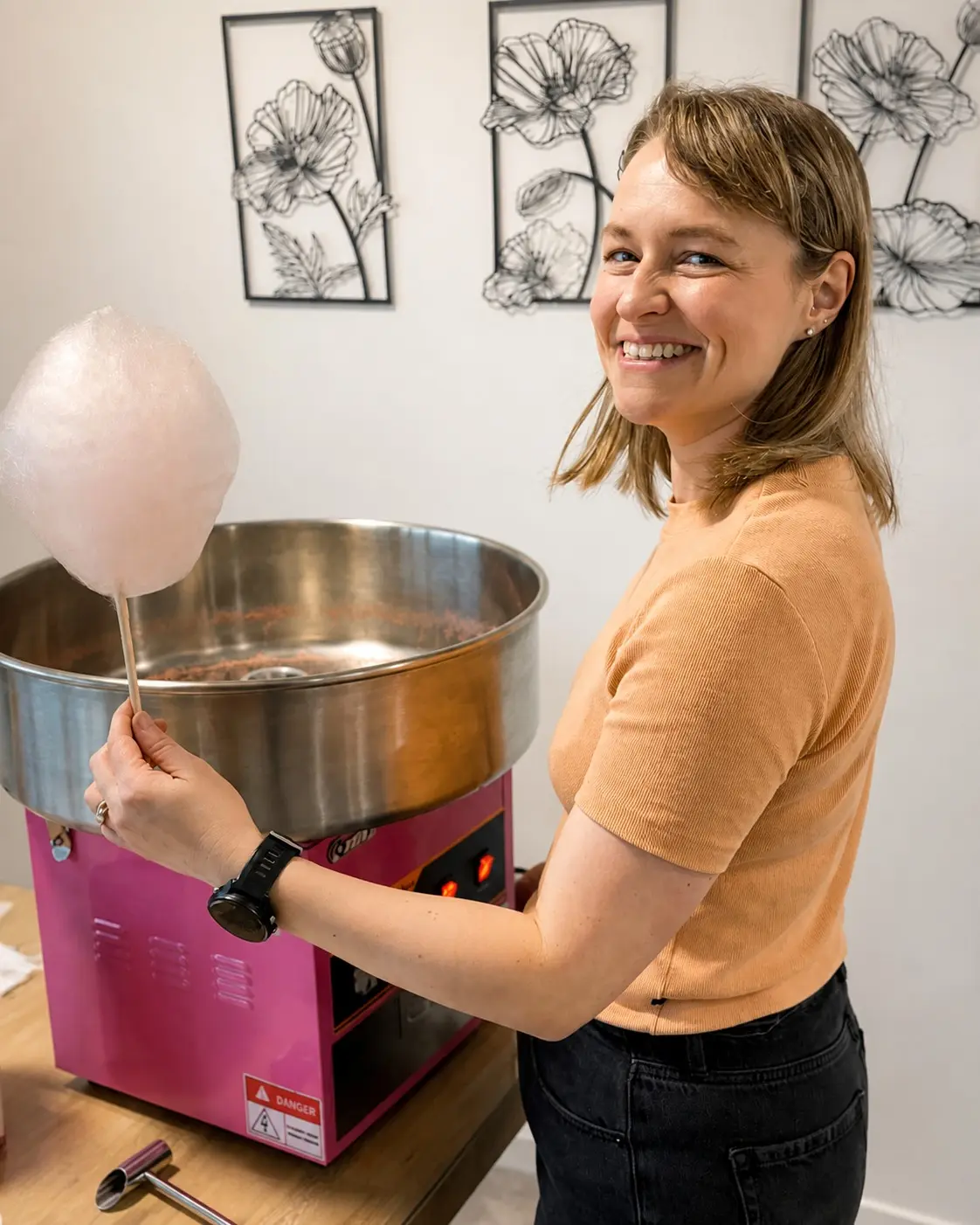 An adult holding freshly made pink candy floss beside Playday’s candy-floss machine.