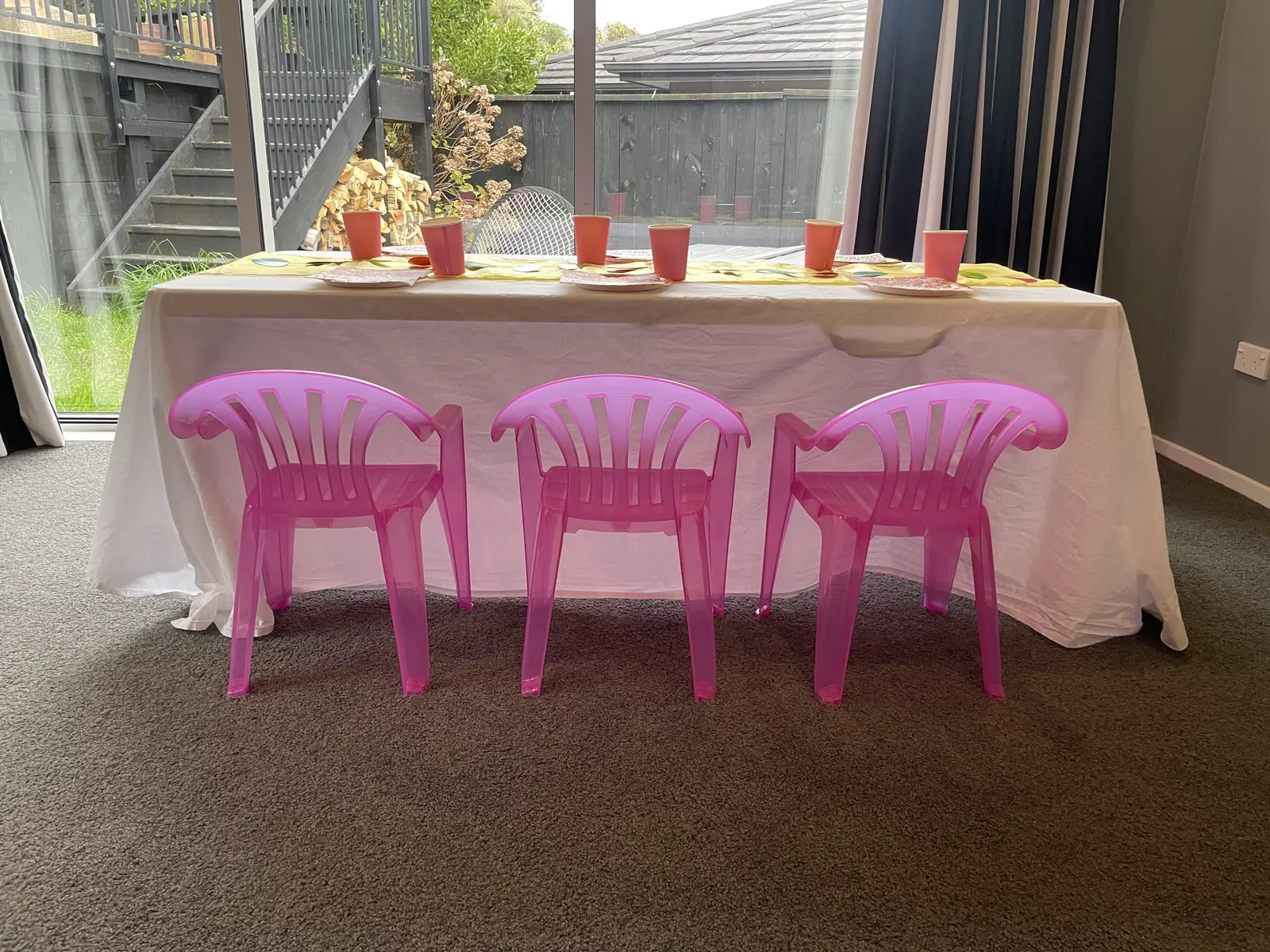 Front view of a children’s table with three bright pink Playday chairs.