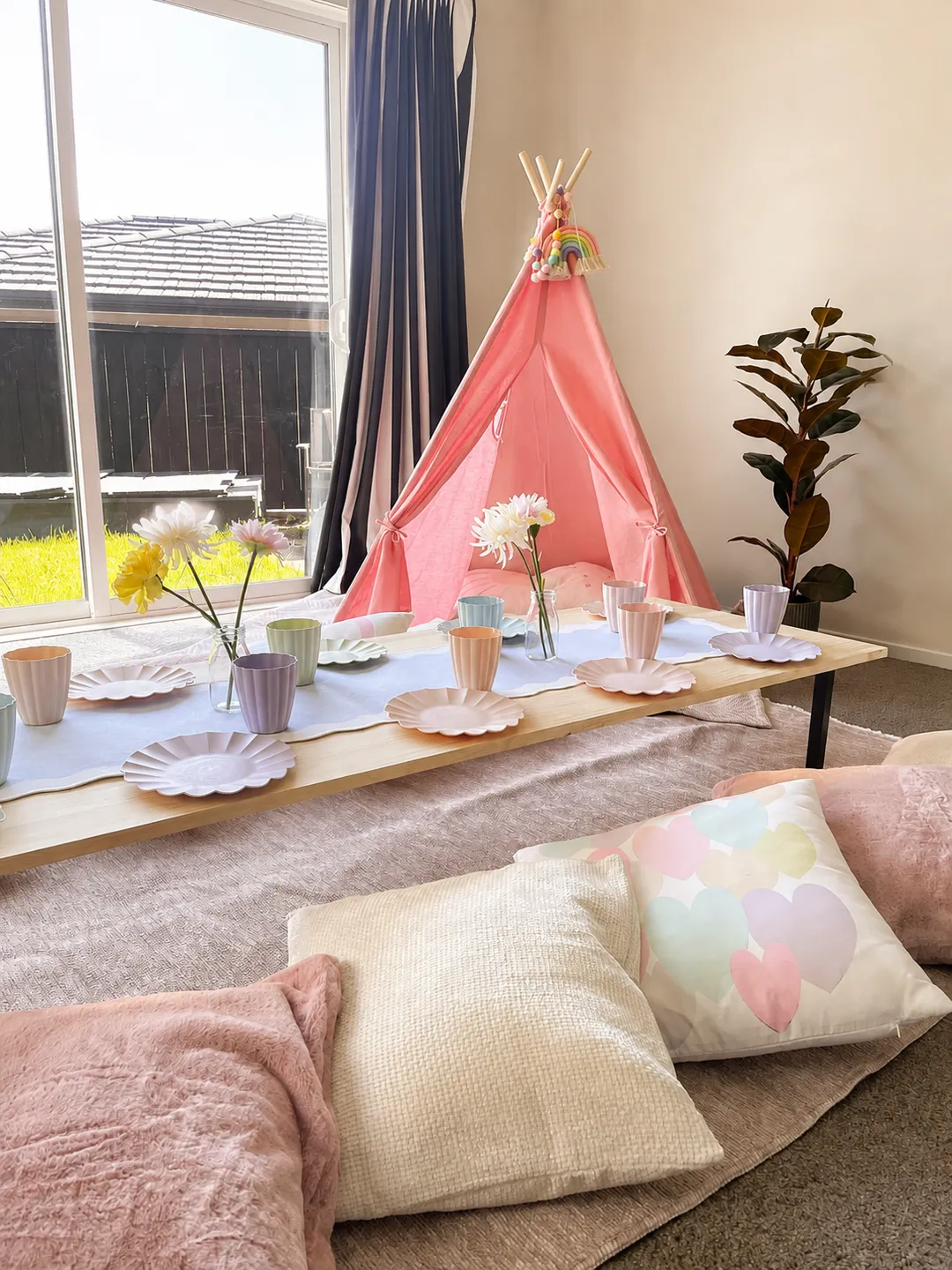 The full children’s picnic setting with floor rugs, soft cushions, a low table and pink teepee.